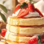 Fluffy Japanese soufflé pancakes served on a plate with syrup and berries